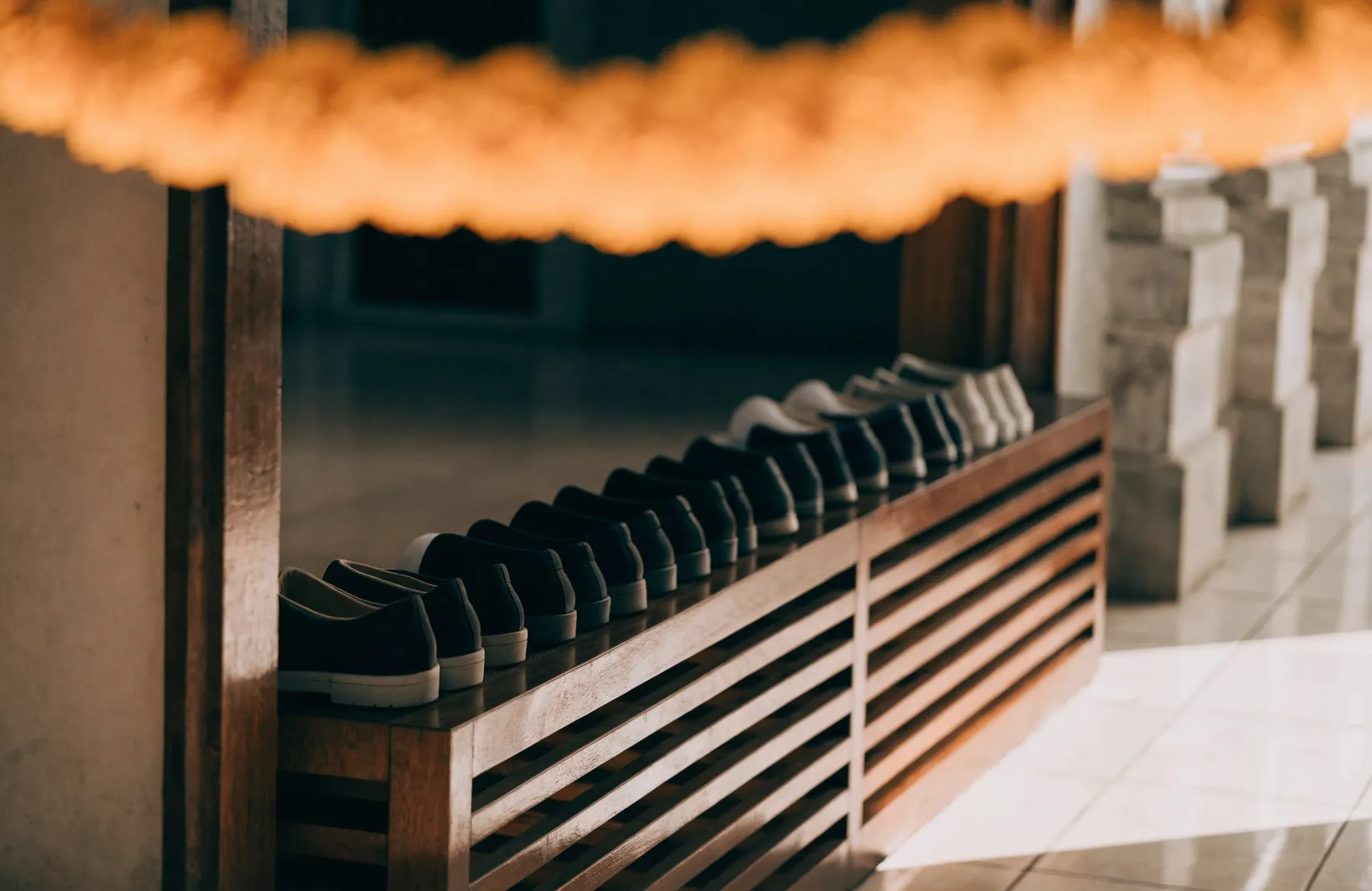 Shoes left neatly on a wooden rack just inside a temple entrance