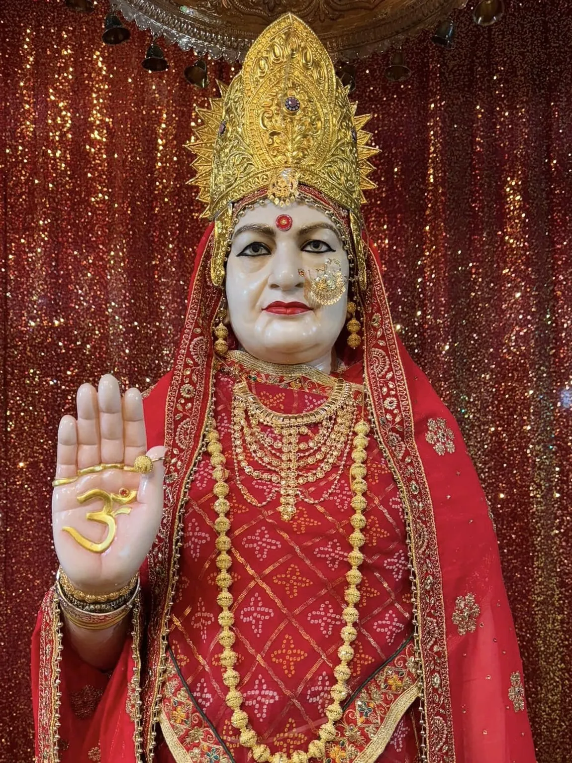 The murti of Maa Bhameshwari on the right of the main altar, her hand raised in blessing
