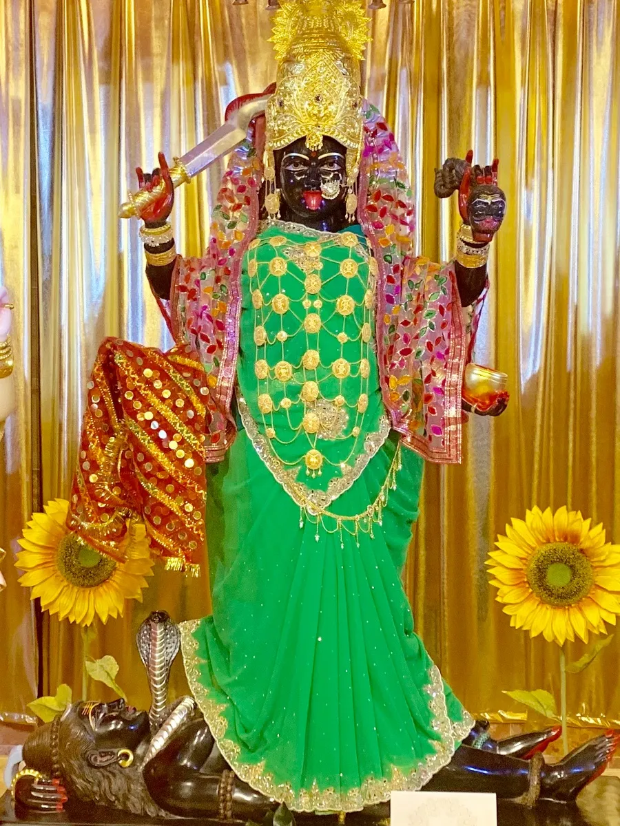 The murti of Maa Kali at the centre of the main altar, dressed in green and gold with her sword raised