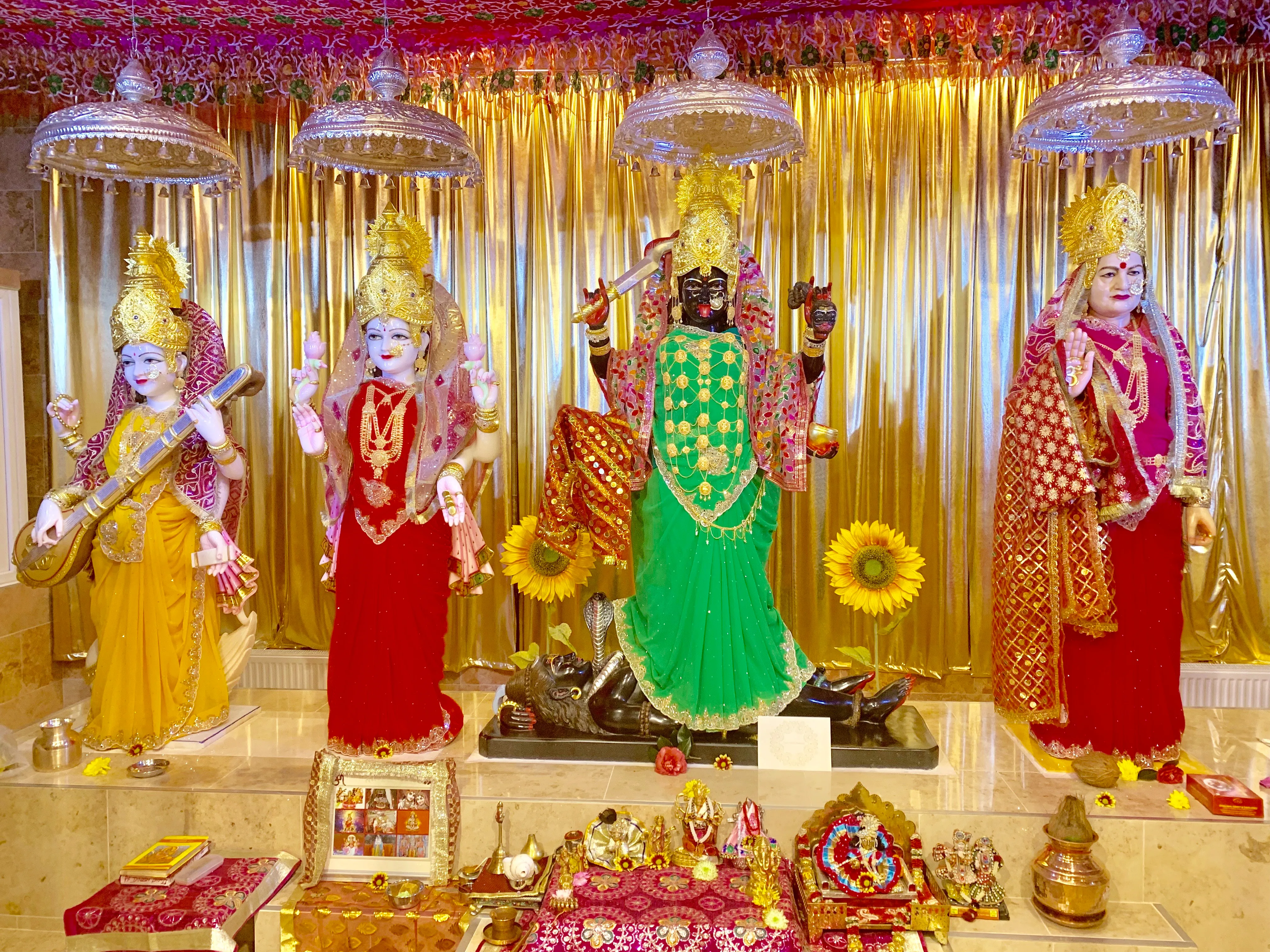 The main altar dressed in gold — Saraswati, Lakshmi, Maa Kali and Maa Bhameshwari beneath silver chhatras