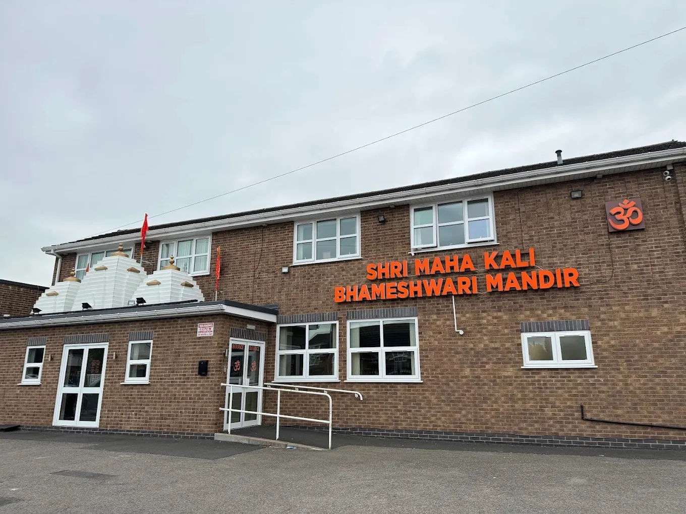 Shri Maha Kali Bhameshwari Mandir on Dilloways Lane, Willenhall — white shikhara domes, an Om emblem and the mandir's name in orange lettering above the entrance