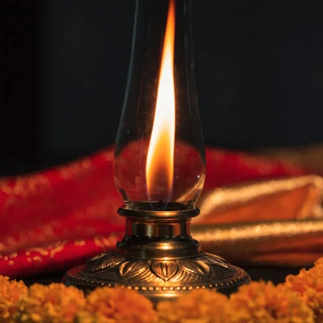 The akhand jyot burning in a brass lamp with a glass chimney, on marigolds