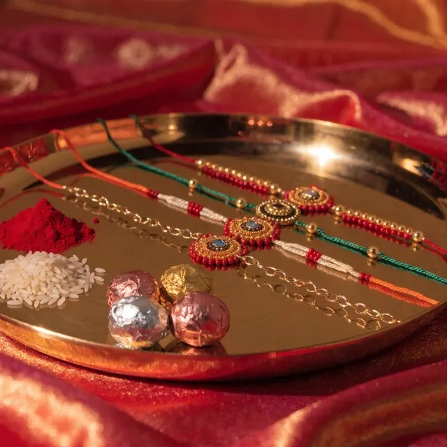 Rakhi threads laid on a brass thali with roli, rice and sweets