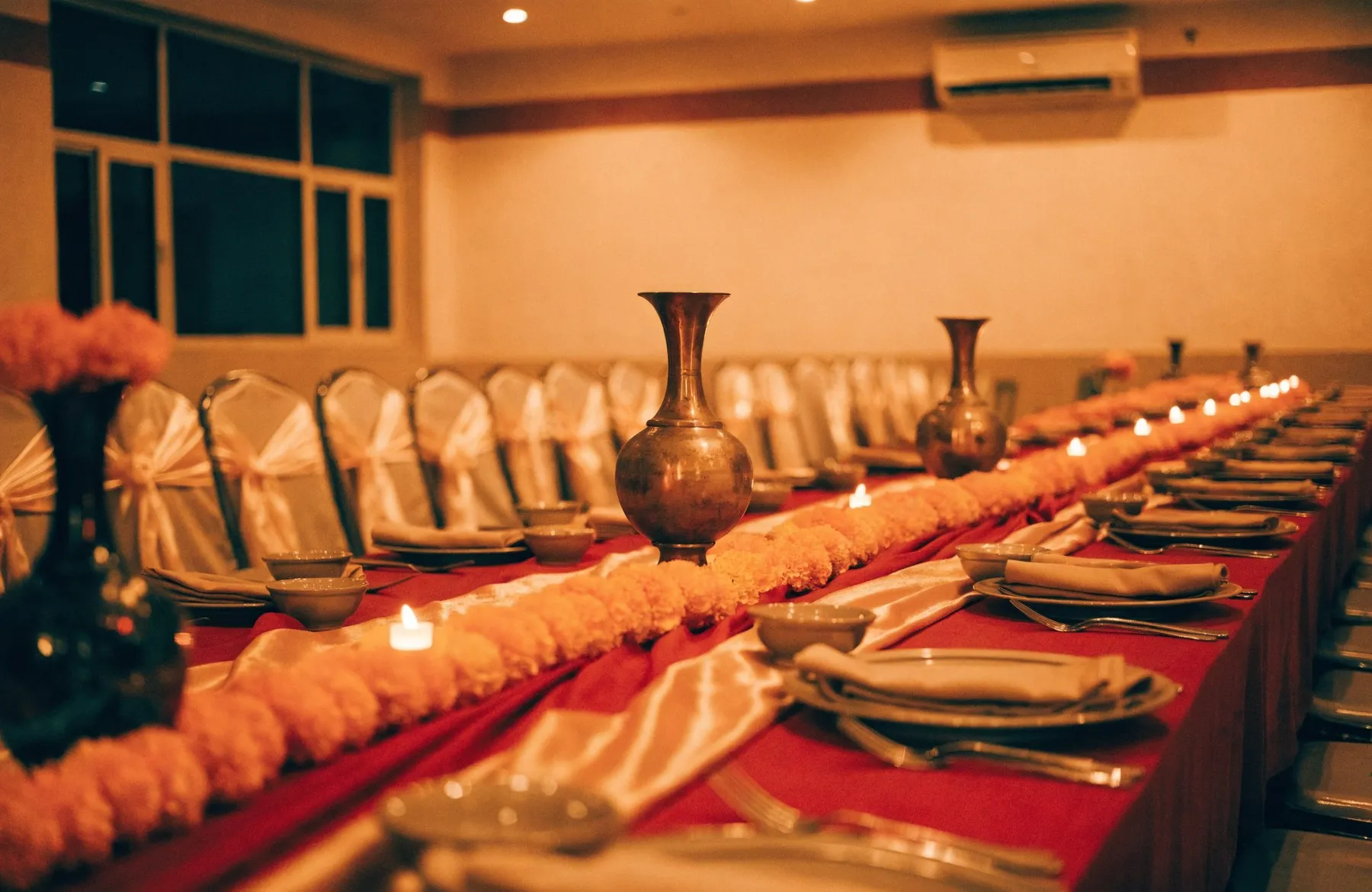 A community hall set with long tables dressed in red and gold for a celebration